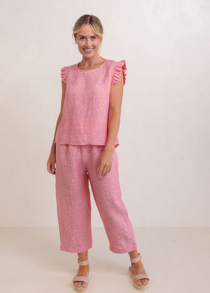 Woman wearing a pink outfit with ruffled sleeves on a white background