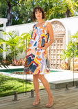 Woman in a colorful dress standing on a wooden deck with a pool and garden in the background